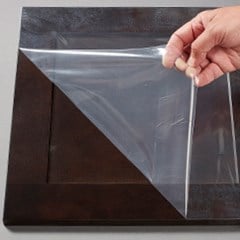  A surface protection film is being peeled from a wooden cabinet door.