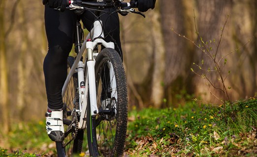 A person rides a white mountain bike on a grassy trail.