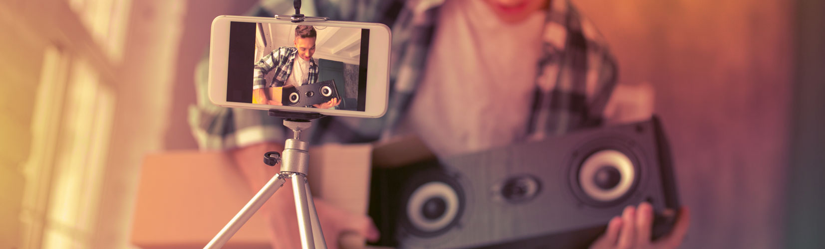 A man records a video of himself while unboxing new speakers