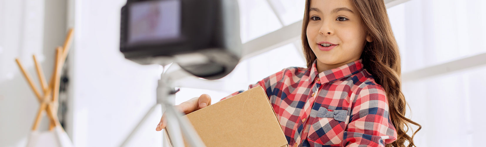 girl in red plaid shirt holding a cardboard box package