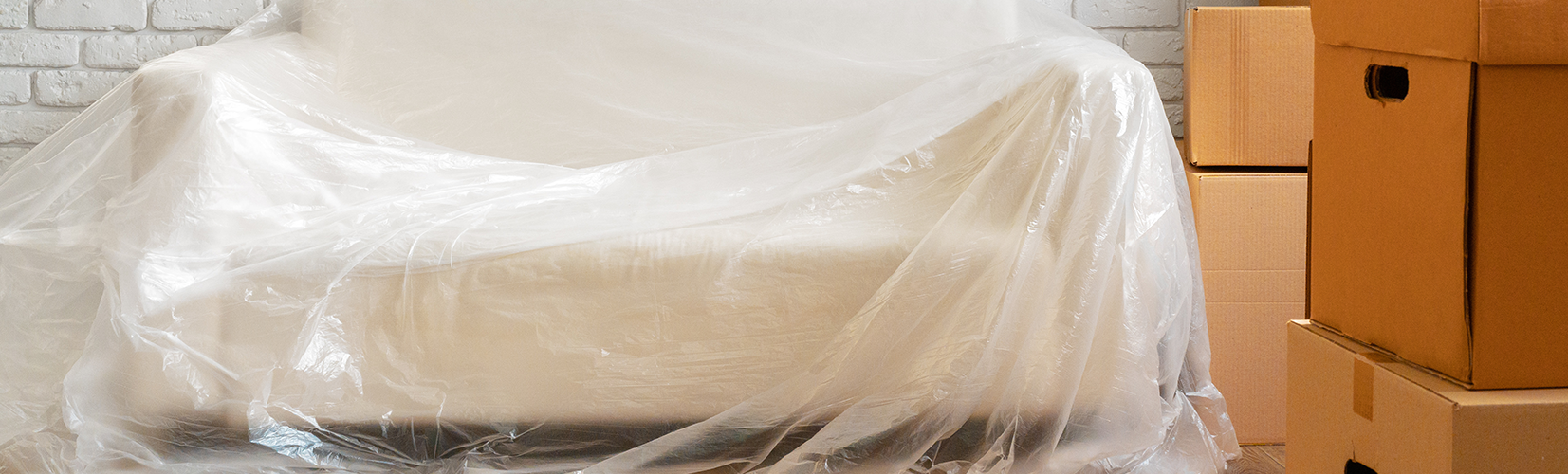 white couch covered with translucent plastic to protect from dust