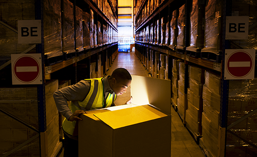 Person opening big box inside warehouse full of packages