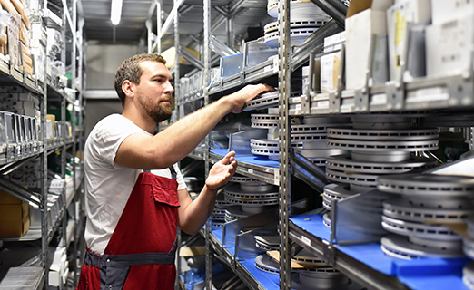 Worker arranging metal products in shelf