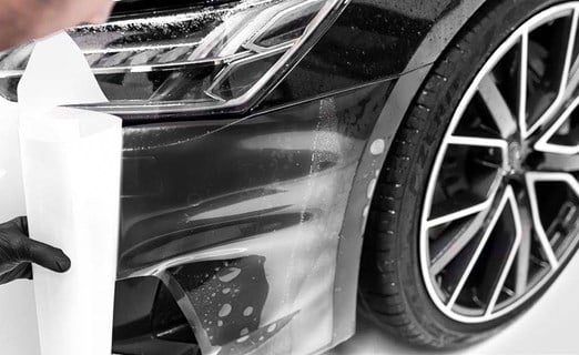 protective film being placed on black car fender