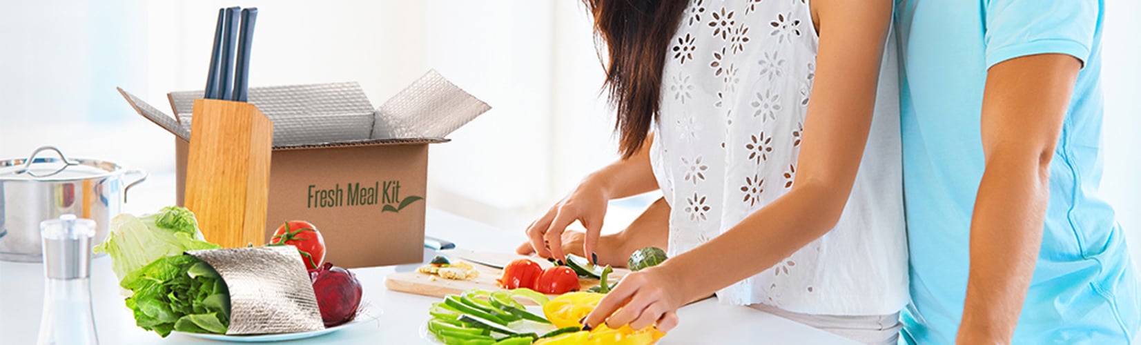 Couple preparing vegetable dish inside white kitchen