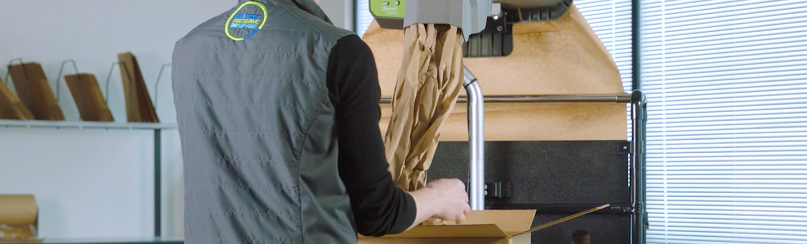  A person using an EasyPack Quantum Pro packaging machine to dispense protective paper into a cardboard box for efficient packing.