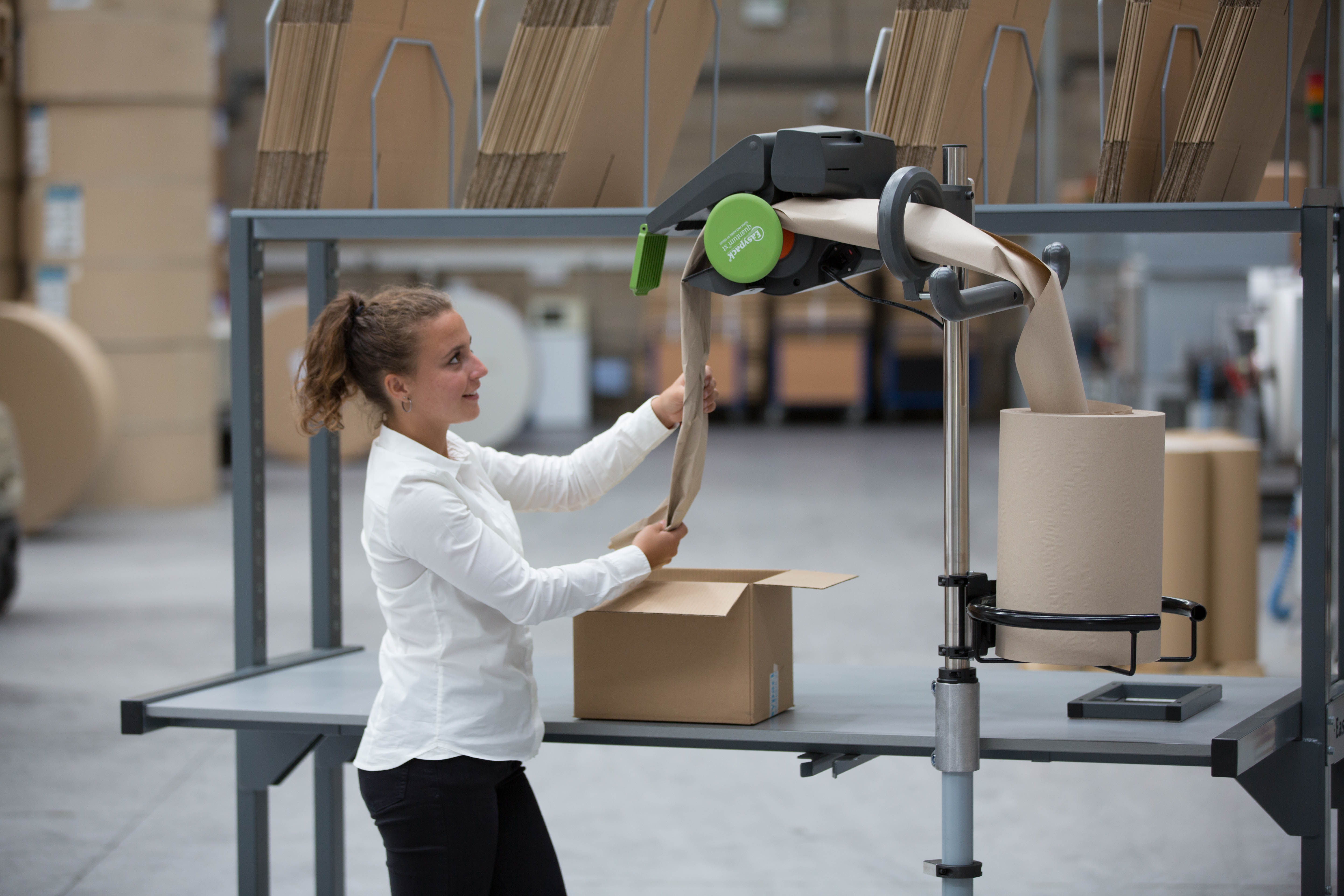 Warehouse worker uses the Quantum XT machine to pack a cardboard box with paper packaging material.