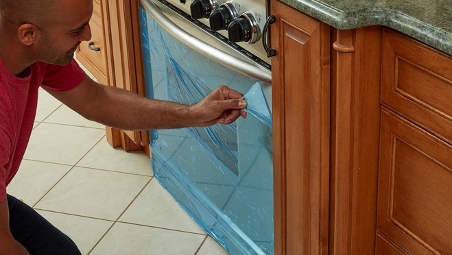 Person peeling off blue protective covering on gas range