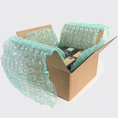 An open cardboard box lined with HC Renew inflatable air cushion packaging, designed to protect the contents during shipping. The box contains items securely enclosed within the cushioning material.