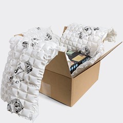 An open cardboard box lined with HC Renew PCR inflatable air cushion packaging, designed to protect the contents during shipping. The box contains items securely enclosed within the cushioning material.