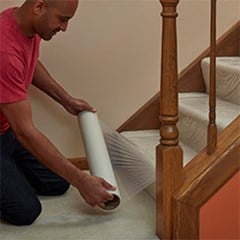 Carpet protection film being laid out on carpeted stairs.
