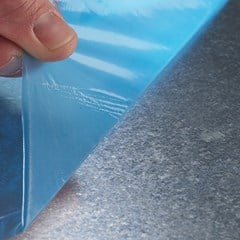 Temporary film protection is peeled off a metal surface.