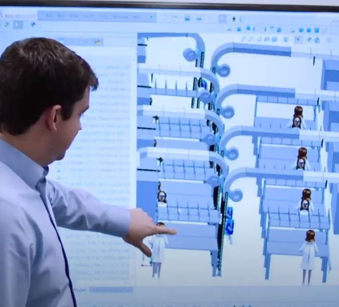 An engineer is reviewing a conveyance system design on a large screen.