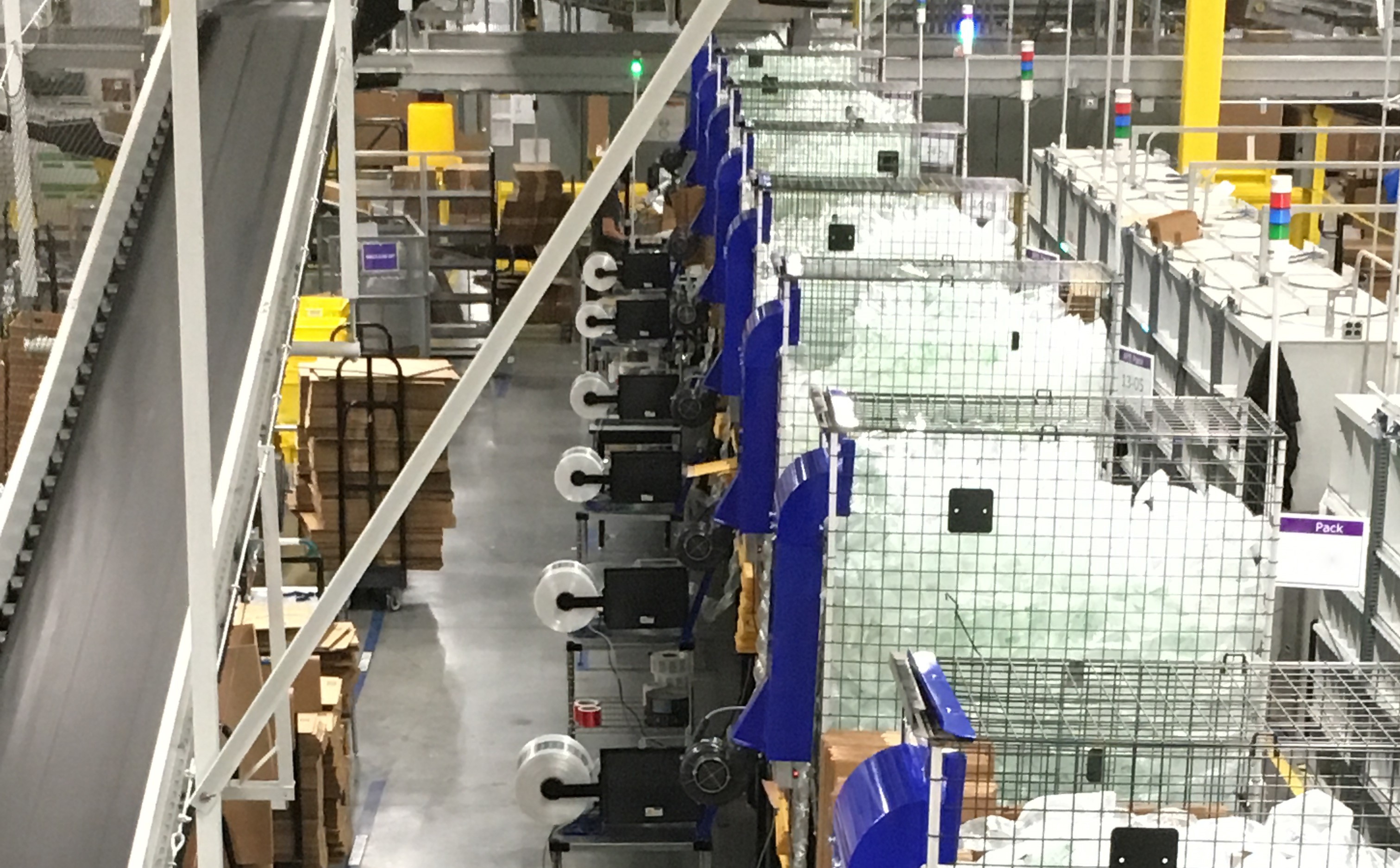 Multiple custom integrated fulfillment systems are operating inside a large warehouse.